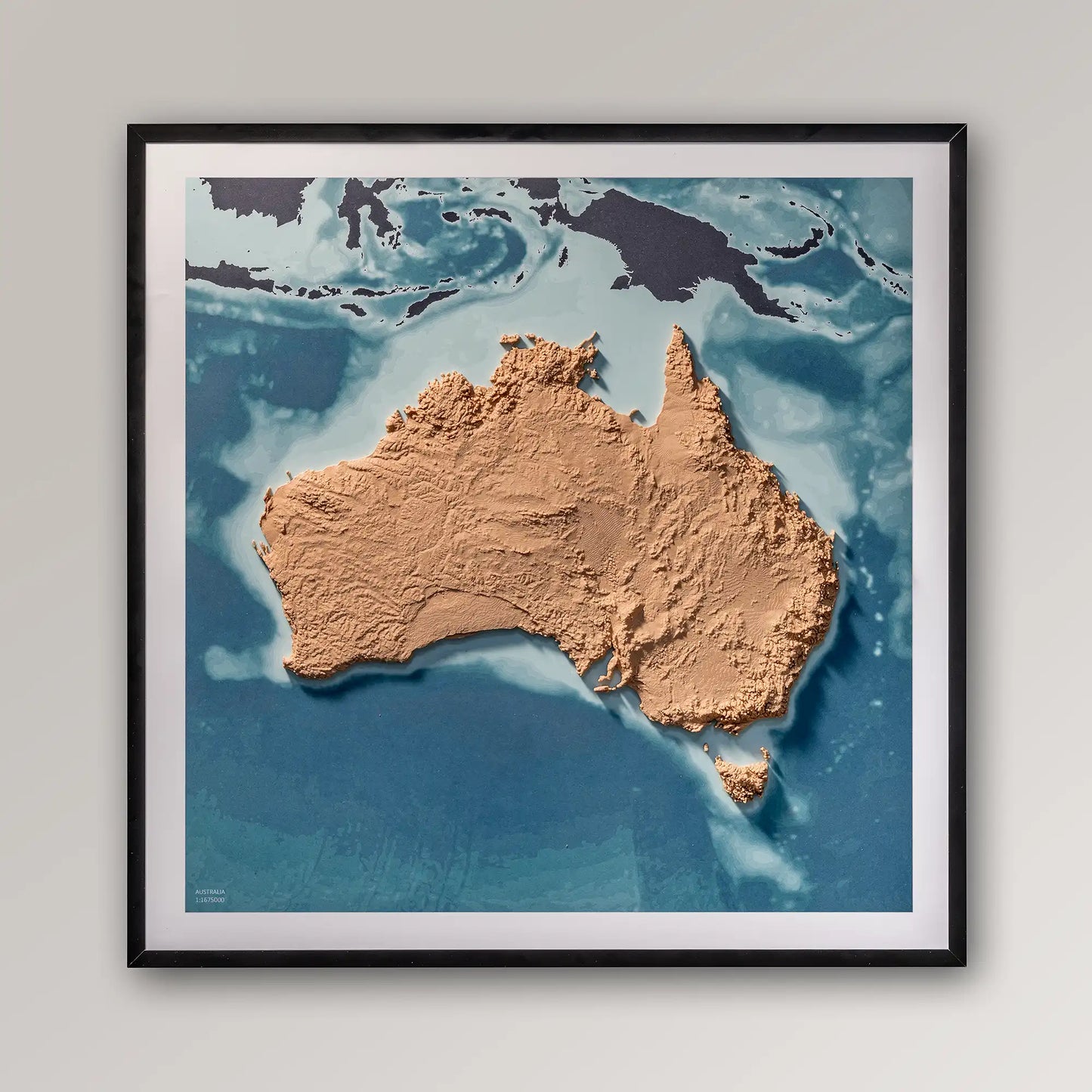 Framed 3D topographic map of Australia, 40x40cm art board inside a black frame on a light grey wall – TerraFrames