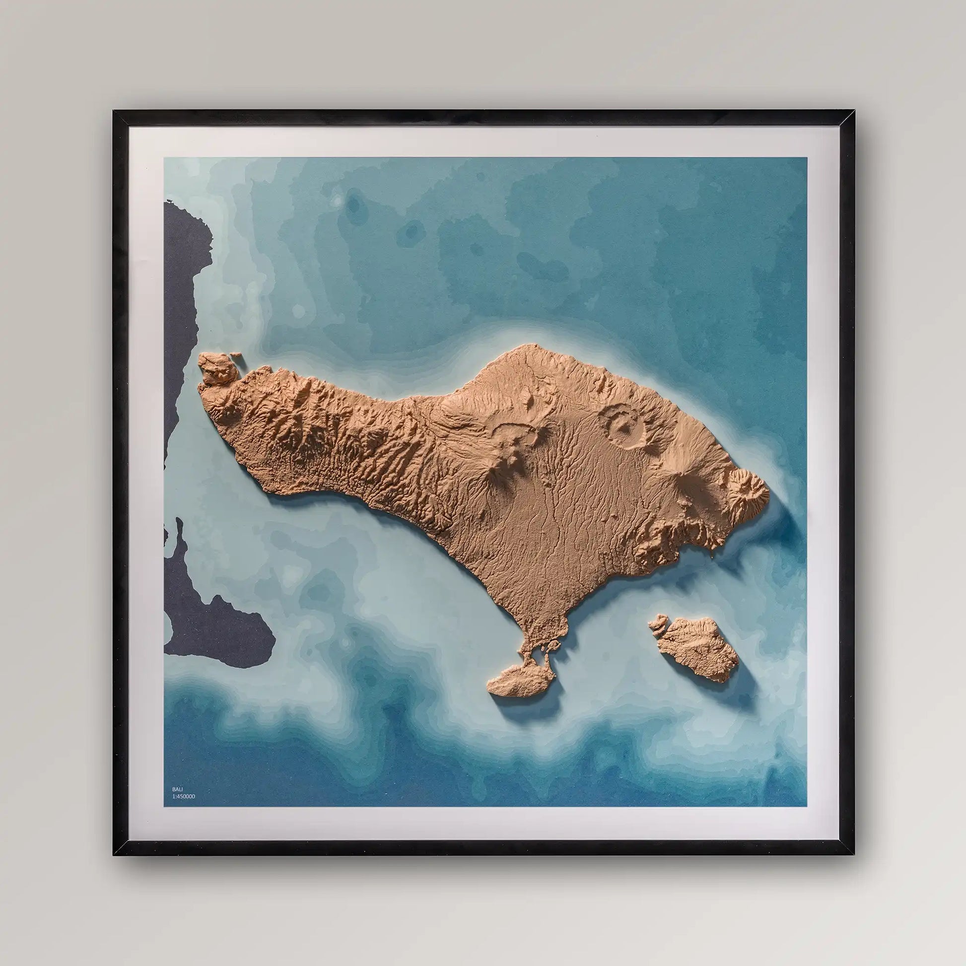 Framed 3D topographic map of Bali, 40x40cm art board inside a black frame on a light grey wall – TerraFrames