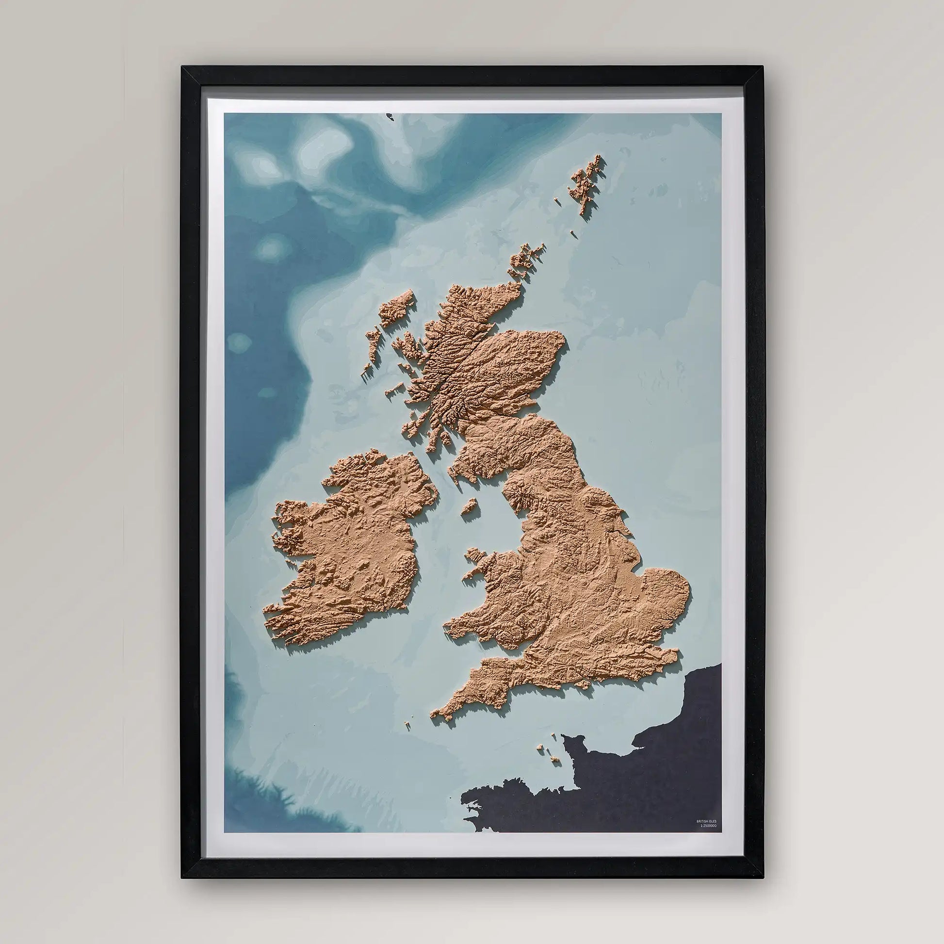 Framed 3D topographic map of Scotland, England and Ireland inside a black frame on a light grey wall – TerraFrames
