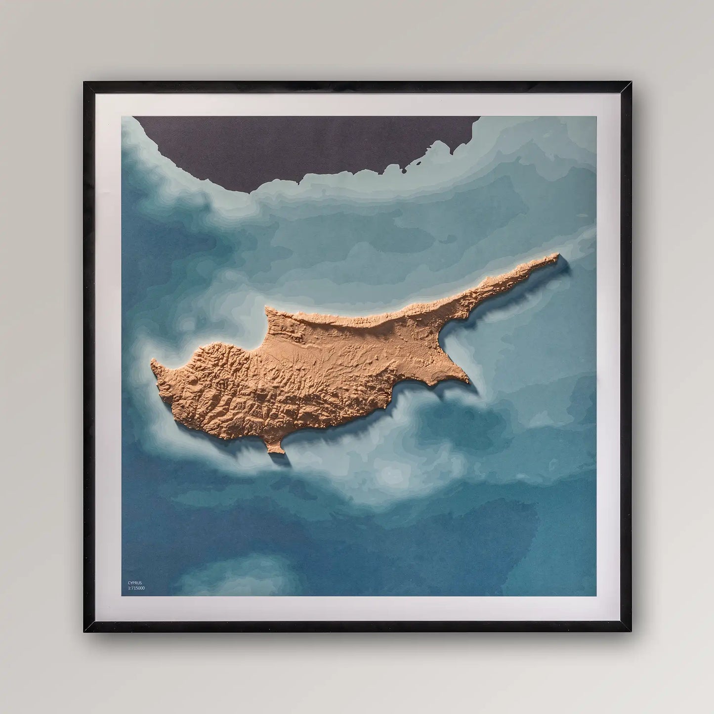 Framed 3D topographic map of Cyprus, 40x40cm art board inside a black frame on a light grey wall – TerraFrames