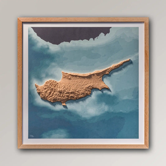 Framed 3D topographic map of Cyprus, 40x40cm art board inside an oak frame on a light grey wall – TerraFrames