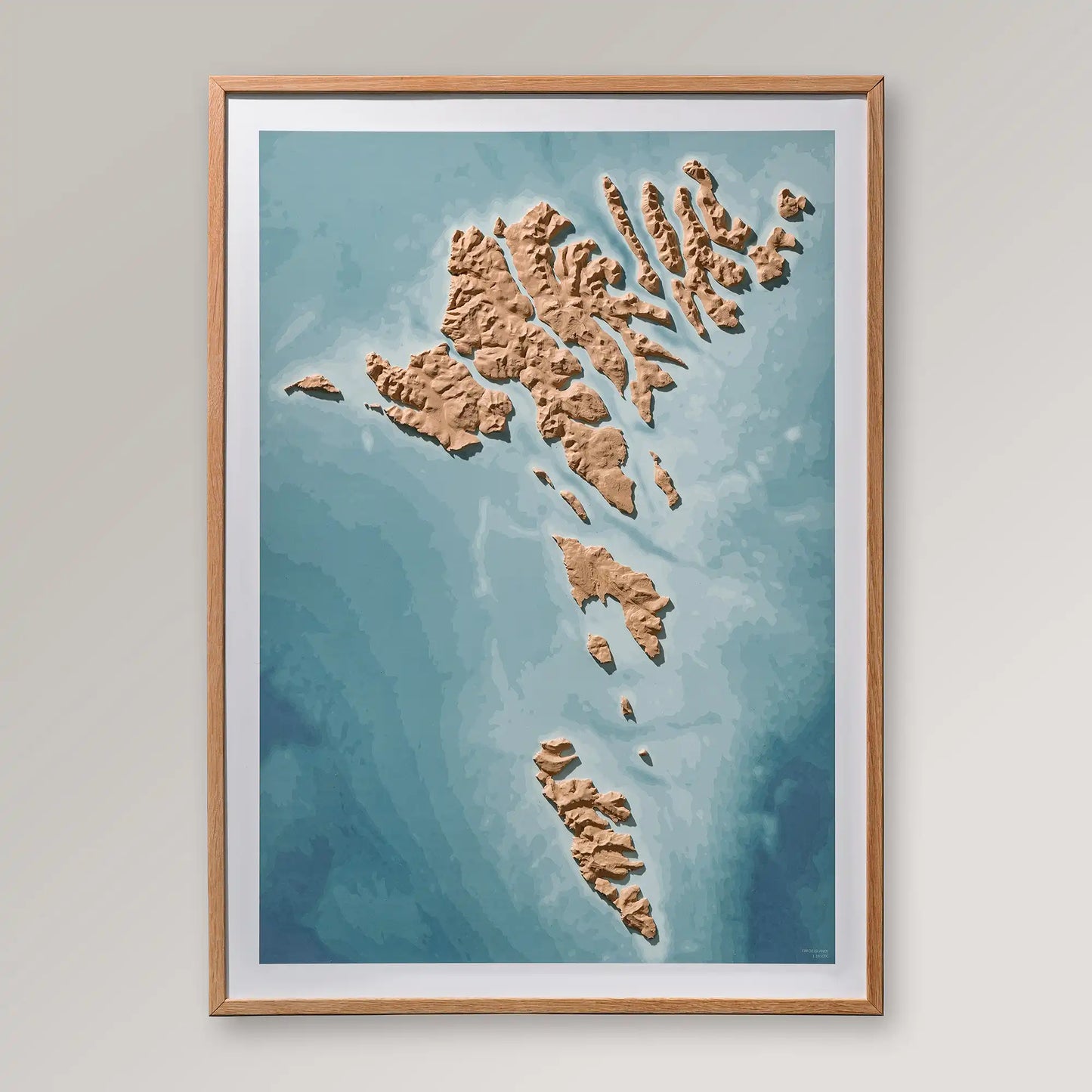 Framed 3D topographic map of the Faroe Islands inside an oak frame on a light grey wall – TerraFrames