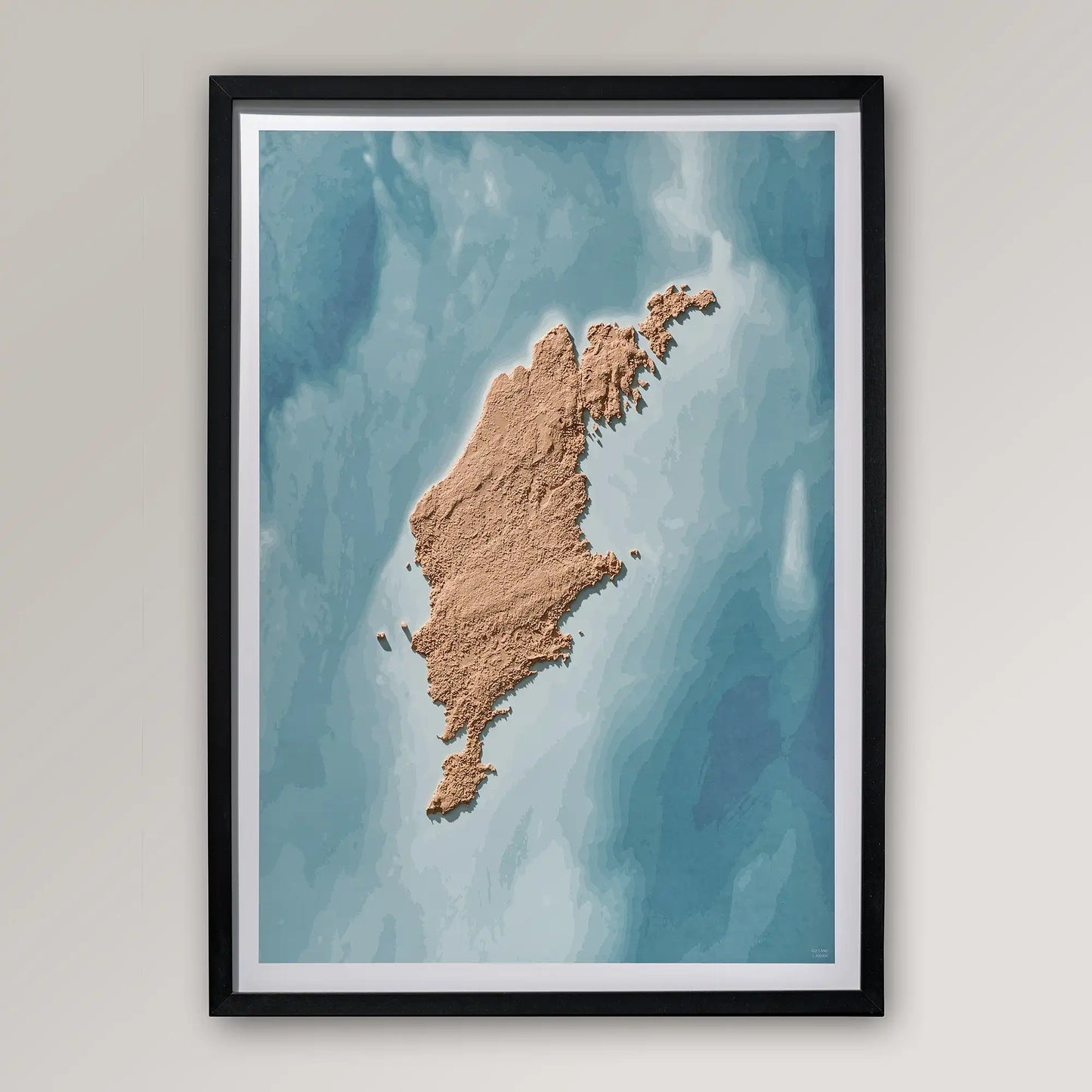 Framed 3D topographic map of Gotland inside a black frame on a light grey wall – TerraFrames
