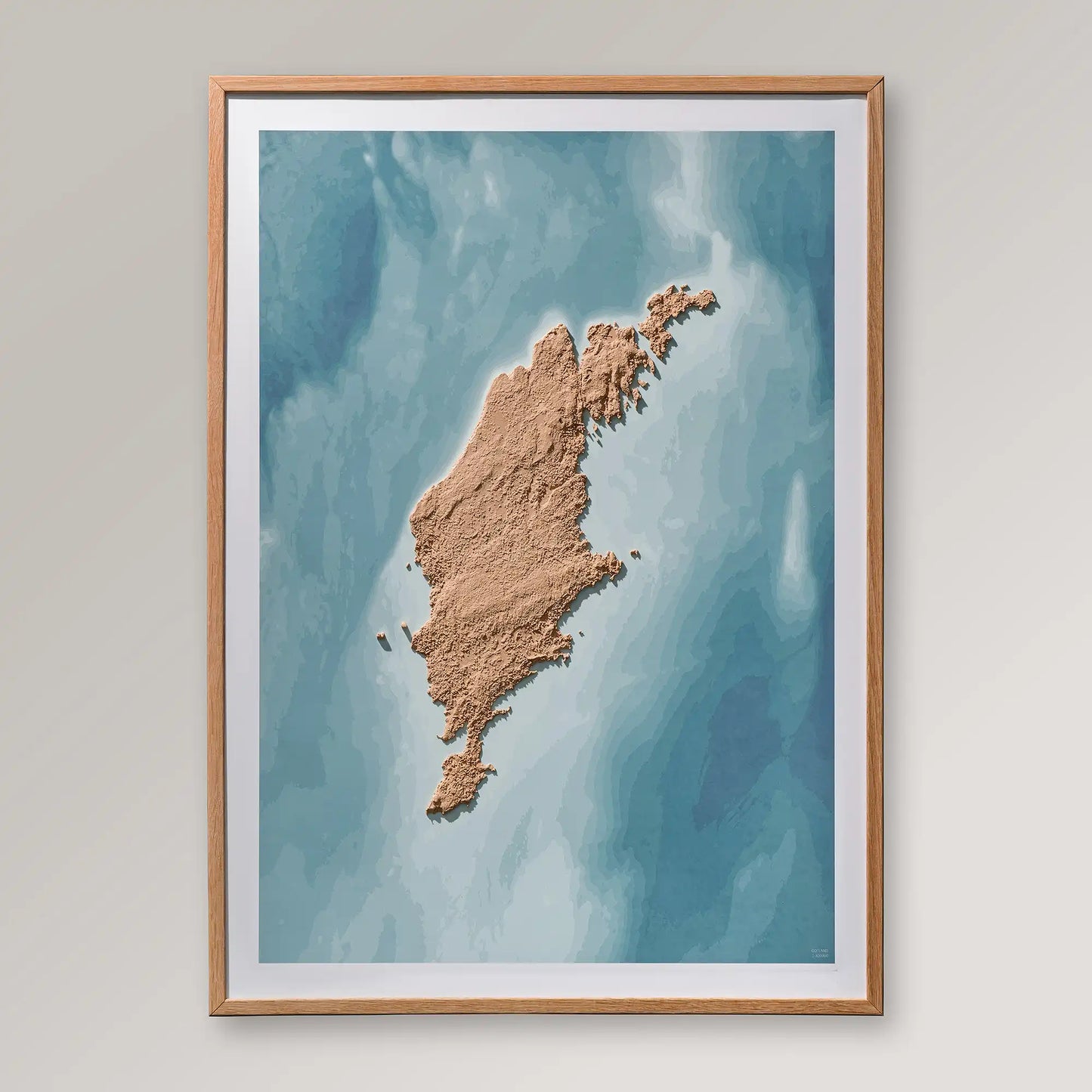 Framed 3D topographic map of Gotland inside an oak frame on a light grey wall – TerraFrames