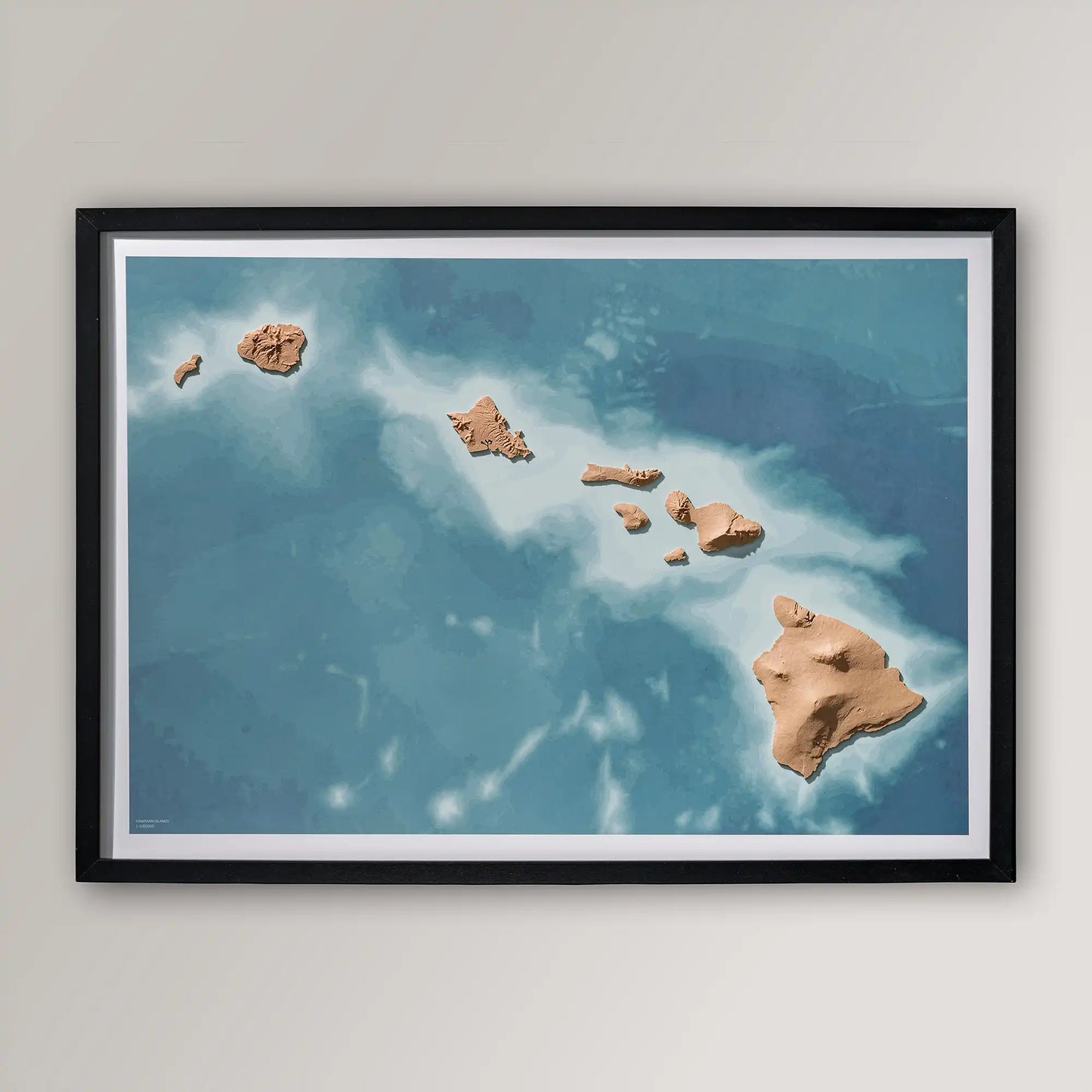 Framed 3D topographic map of Hawaii inside a black frame on a light grey wall – TerraFrames