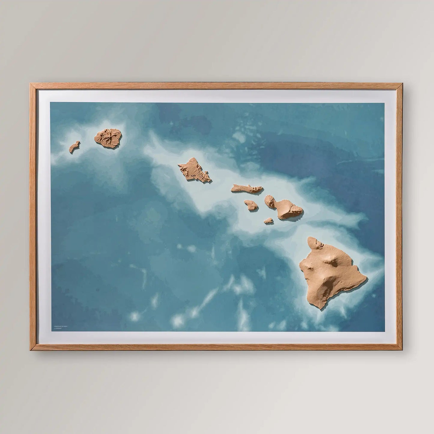 Framed 3D topographic map of Hawaii inside an oak frame on a light grey wall – TerraFrames