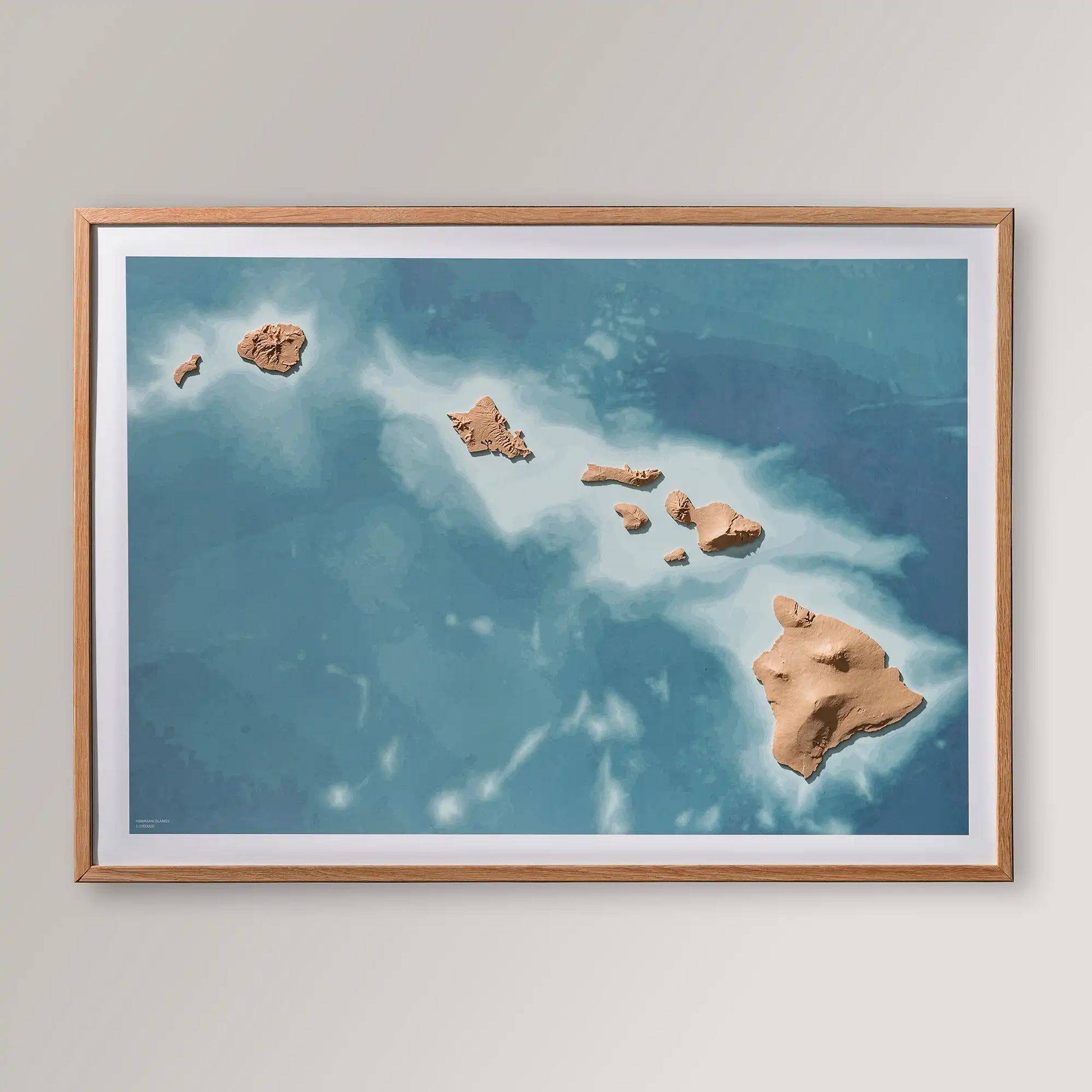 Framed 3D topographic map of Hawaii inside an oak frame on a light grey wall – TerraFrames