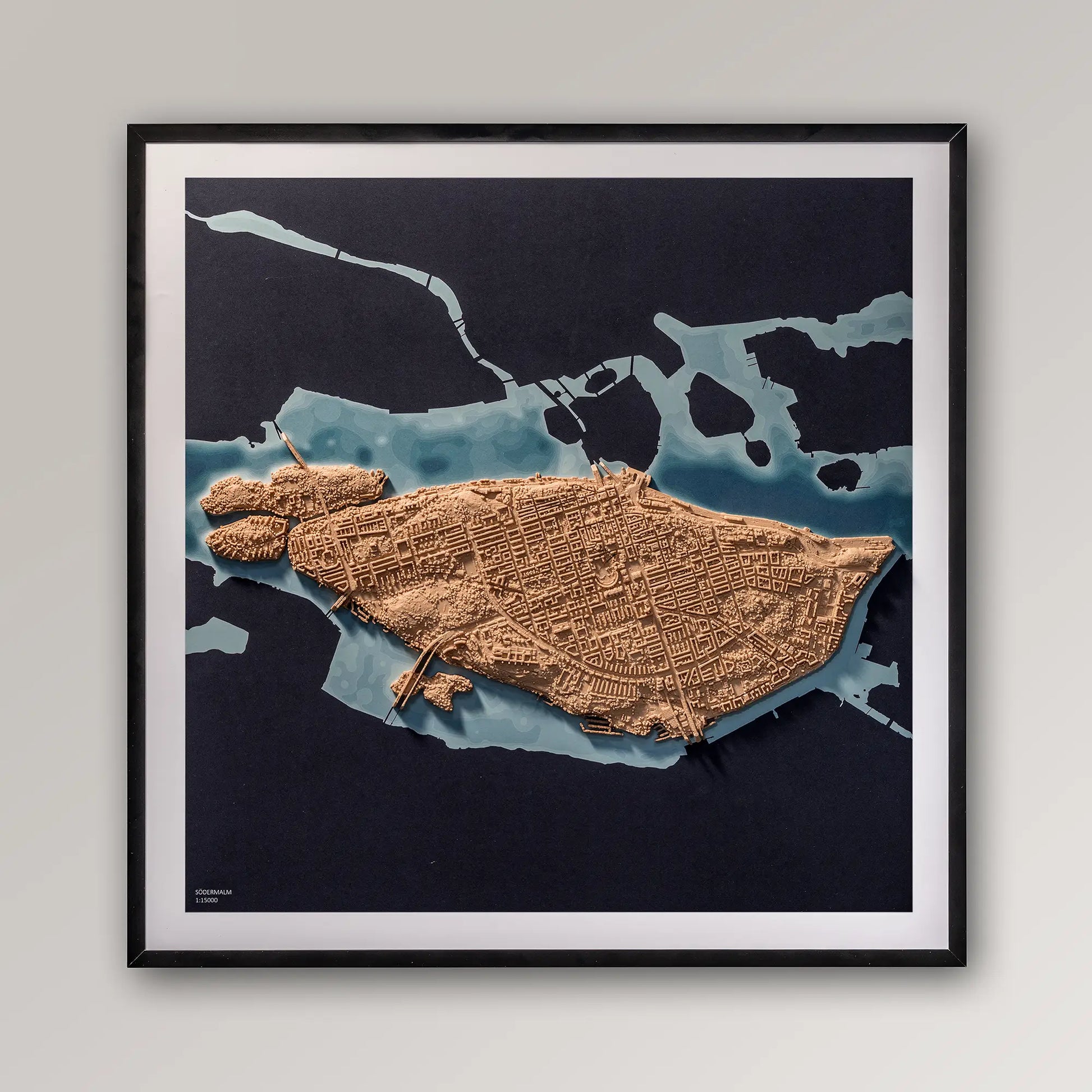 Framed 3D topographic map of Södermalm, Stockholm, 40x40cm art board inside a black frame on a light grey wall – TerraFrames